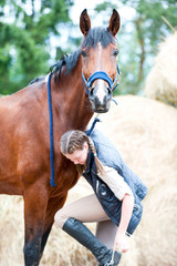 Beautiful bay horse looking in to camera standing near girl