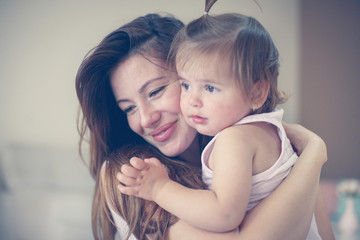 Mother and her cute baby at home. Mother holding little baby in her arms.