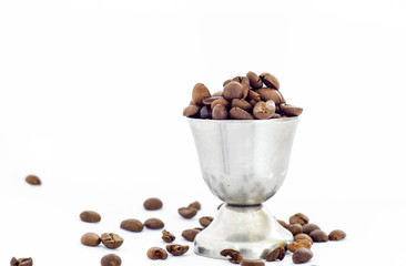 Coffee beans and small metal cup on white background