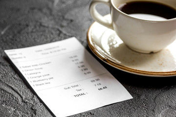 restaurant bill, card and coffee on dark table background