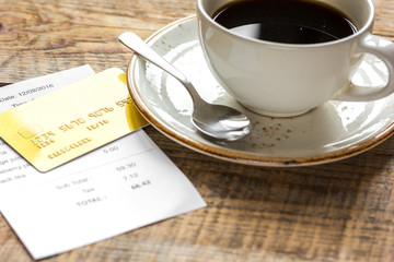 restaurant bill, card and coffee on wooden table background