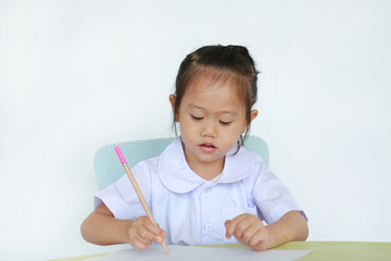 Asian child in school uniform with pencil writing on table isolated on white background.