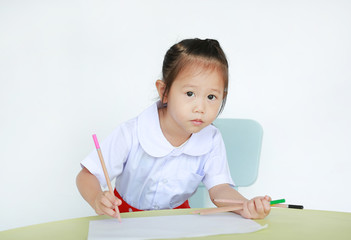Asian child in school uniform with pencil writing on table isolated on white background.