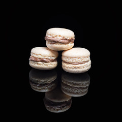 Macaroons stacked isolated on black background with reflection. Traditional french dessert macarons