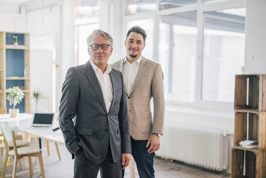 Portrait of confident old and young businessman in office