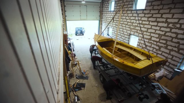 Selfmade Wooden boat in garage workroom with people and truck. preparation to export