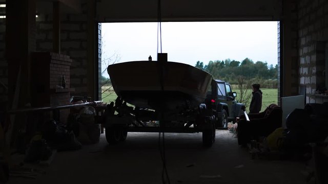 Master and asian assistant movie sailboat on car truck from garage workroom outdoot. Silhouette view static footage. 4k uhd