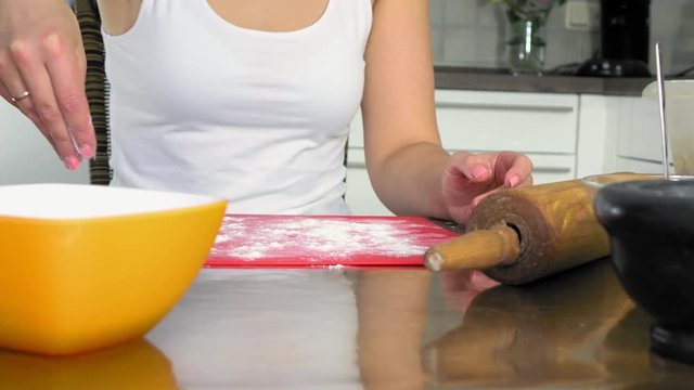 Kneading the dough on the table full of flour . Close up footage of a woman kneading the dough on the wooden table