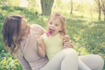 Mother and daughter in the meadow with ice cream.
