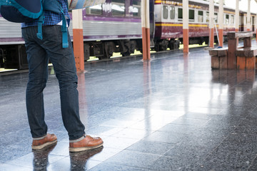 Obraz premium asian man with backpack standing on platform at train station. backpacker or traveler look at map while waiting for train. journey, trip, travel concept