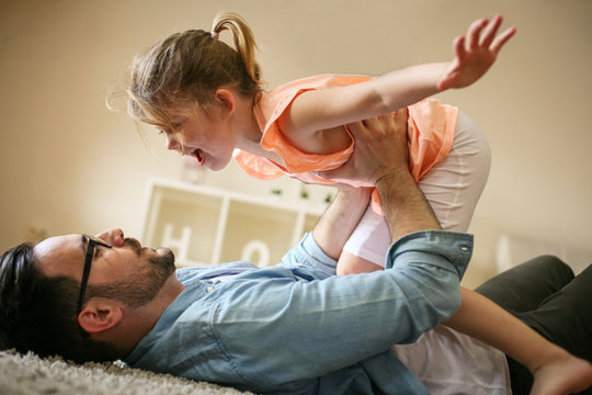 Happy father playing at home with his daughter.