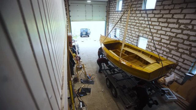 Selfmade Wooden boat in garage workroom with people and truck. preparation to export. Stebilized steadicam shot.