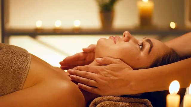Spa facial massage. Brunette woman enjoying relaxing face massage in beauty spa salon. 4K UHD video 3840x2160
