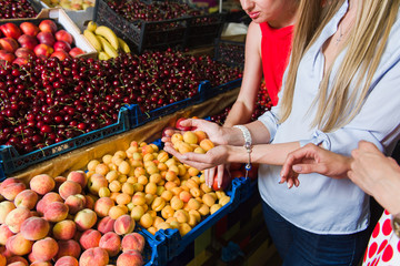 Three young women at grocery market. Women choose fruit. 