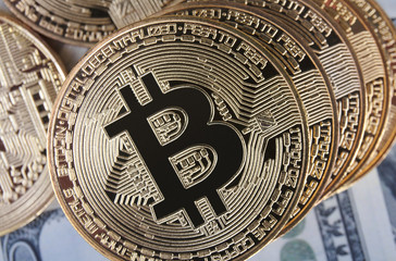 Golden bitcoin coin on us dollars close up