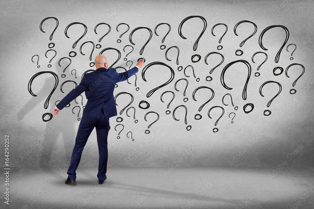 Poster view of a businessman in front of a wall trying to find find answers - daily life concept
