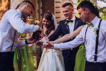 Stylish wedding couple, groomsman and bridesmaids with champagne explosion.