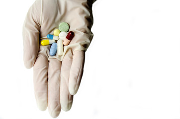 Colored tablets and capsules in a hand clad in latex gloves.