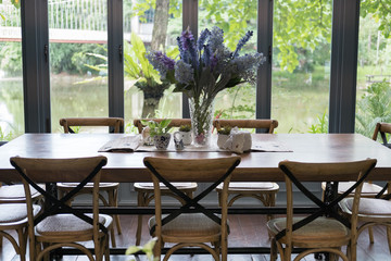 wood table and chair in dining room beside window with lake and garden view. home interior