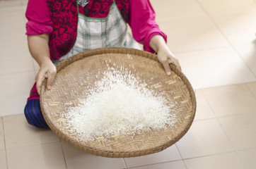 housewife winnowing rice by using bamboo basketwork for separate between rice and rice husk.selective focus shot