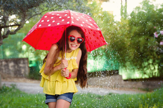 girl in splashing water under umbrella