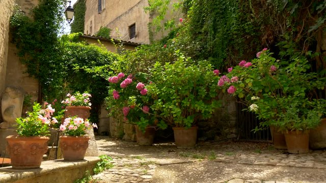 Inside ancient village Lacoste in Provence, France. Patio with flowers and stone walls