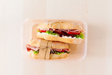 Sandwich with fresh bread, with Italian ham and fresh tomatoes, lettuce in a lunchbox, copy space © irynagrygorii