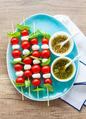 Appetizer in the form of caprese salad in the form of small shish kebabs for a summer healthy snack. On a wooden background