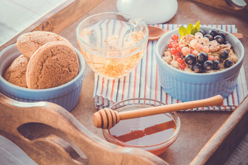 Oatmeal porridge with berries, tea and cookies for breakfast