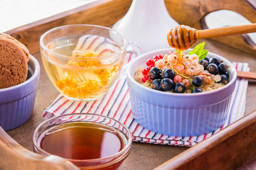 Oatmeal porridge with berries, tea and cookies for breakfast