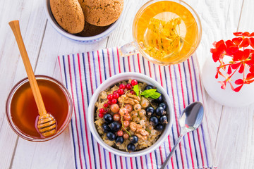 Oatmeal porridge with berries, tea and cookies for breakfast
