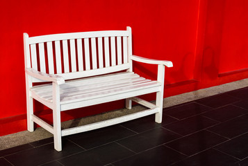 Wood white bench beside the red wall background
