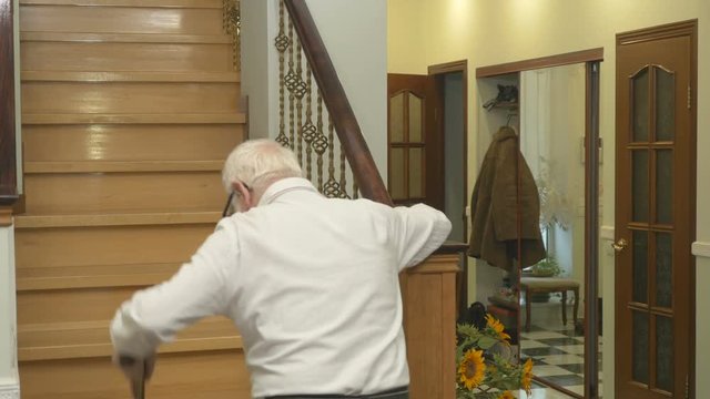 Kind old man leaning on the cone walks upstairs