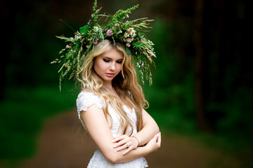Portrait of a beautiful bride in a white dress and a wreath of Forest flowers