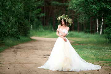 Beautiful bride in a white dress with a wreath of flowers