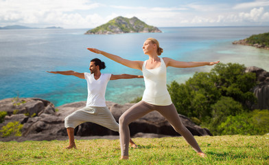 couple making yoga in warrior pose at seaside