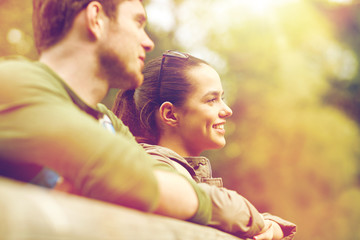 Obraz premium smiling couple with backpacks on bridge in nature