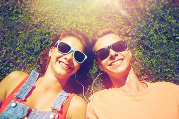 happy teenage couple with earphones lying on grass