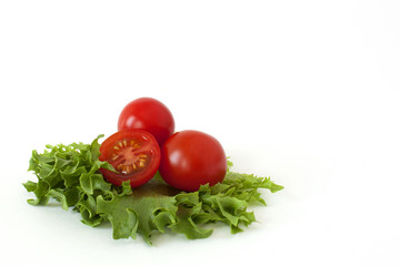 Several cherry tomatoes on fresh lettuce leaves on a white background