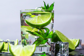 Mojito cocktail with lime, ice cubes and mint in highball glass on a black background Copy space