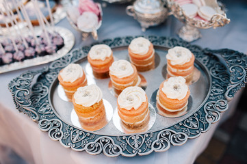 sweet bar with muffins cakes, sweets, fruits and candle holders in area of wedding party