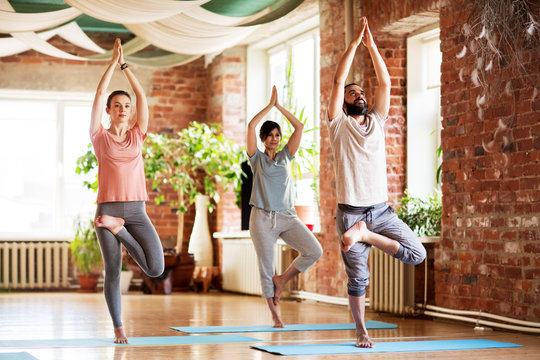 group of people doing yoga tree pose at studio