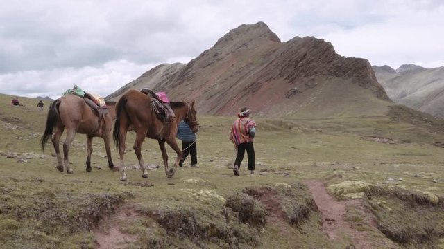 Peruvian men wearing a highlander hats walking with horses on the mountains of Peru. Slow motion