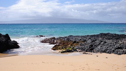 Private beach with sand and lava rocks in Maui Hawaii