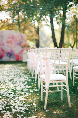 Wedding ceremony with decorations, roses petals and white chair