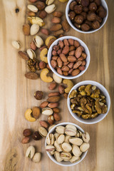 Four bowls with nuts on a  wooden table.