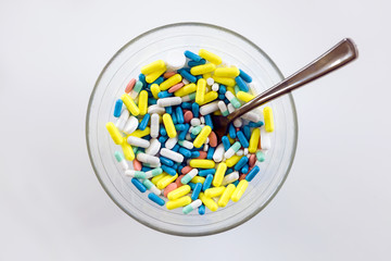 Assorted pharmaceutical medicine pills, tablets and capsules in a bowl.