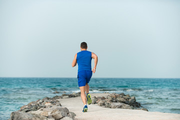 Fototapeta na wymiar Young runner back view athlete running along beach