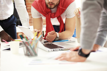 Teamwork,brainstorming concept.Young creative managers team working with new startup project in modern office. Contemporary notebook on wood table.