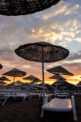 Colorful sunrise on the beach against the background of the sea and the mountains. Rest on the sea. Beach umbrellas and skiers.